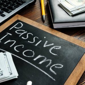 Passive income inscription on the board and a bundle of bills.