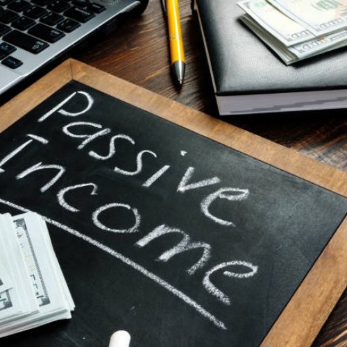Passive income inscription on the board and a bundle of bills.